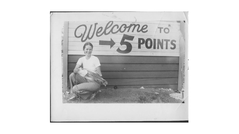 Woman with big fish at the Five Points sign